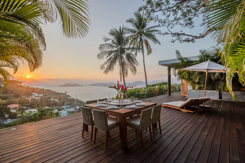 This modern house has a large rooftop deck that's set up for alfresco dining, and glass railings make sure that the view is unobstructed. #RooftopDeck #GlassRailings #AlfrescoDining