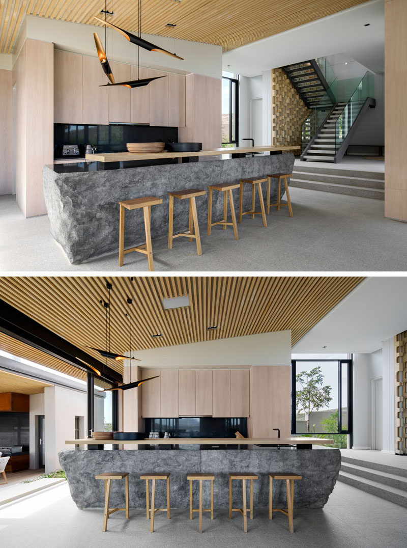 In this modern kitchen, the kitchen island has been created using rough solid blocks of granite, with a highly polished top that serves as the counter, and contrasts the light wood cabinetry and breakfast bar. #GraniteIsland #KitchenDesign #ModernKitchen #Granite