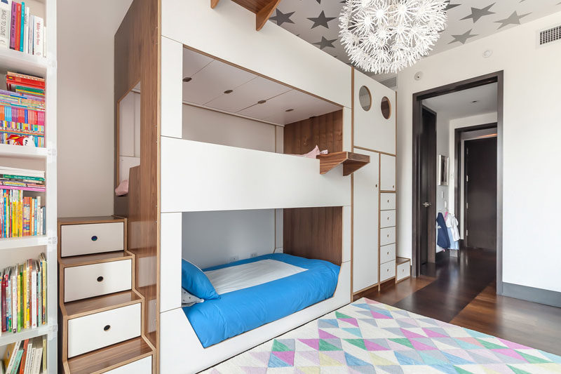 This modern triple bunk bed has two dedicated sets of stairs for the middle and top bunks, built-in storage, and hanging tray tables for each bed. #BunkBed #TripleBunkBed #KidsRoom #Bedroom #ModernBedroom