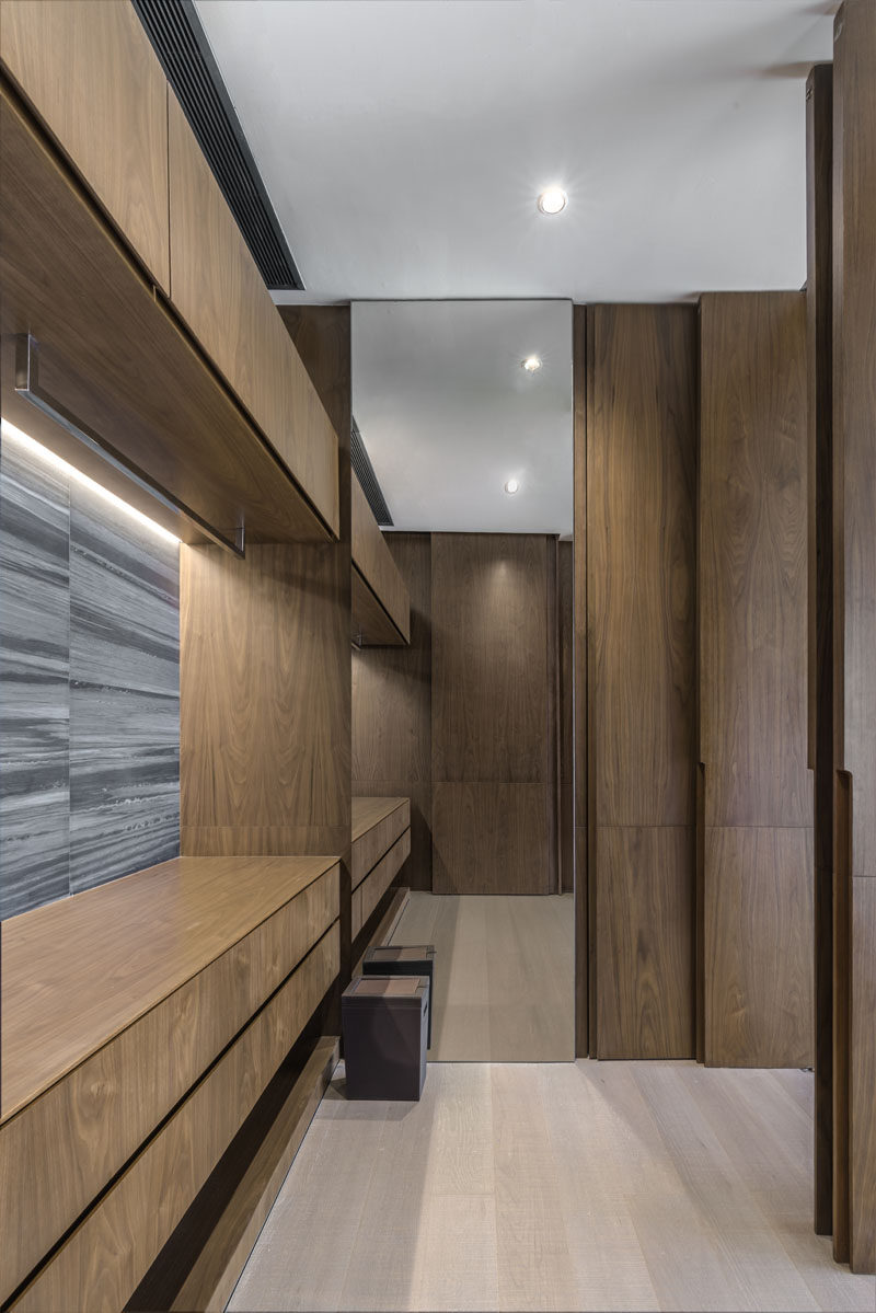 This modern walk-in closet features warm wood cabinets and a floor-to-ceiling mirror. #ModernCloset #WalkInCloset #WoodCabinets