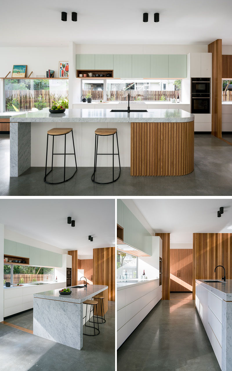 In this modern kitchen, simple and minimalist cabinets have been paired with a large island with a curved end. At the end of the kitchen is a large pantry with plenty of storage. #Kitchen #ModernKitchen #Pantry