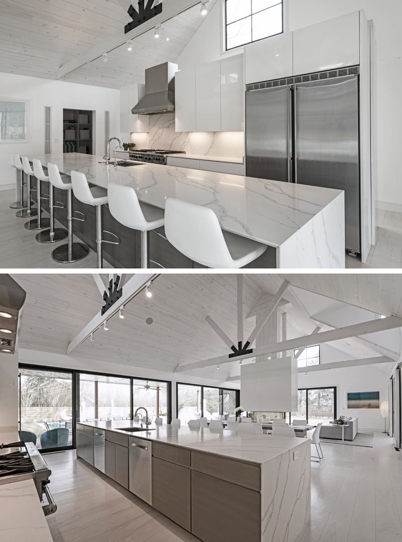 In this modern kitchen, white cabinets have been paired with wood and stainless steel elements. The long 16 foot kitchen island has enough room to seat eight people. #ModernKitchen #KitchenDesign #LongKitchenIsland