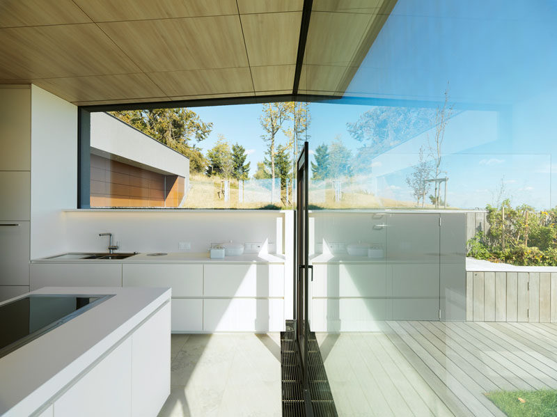 This minimalist, white kitchen, features large windows for maximizing the views and the natural light. #WhiteKitchen #Windows #ModernKitchen