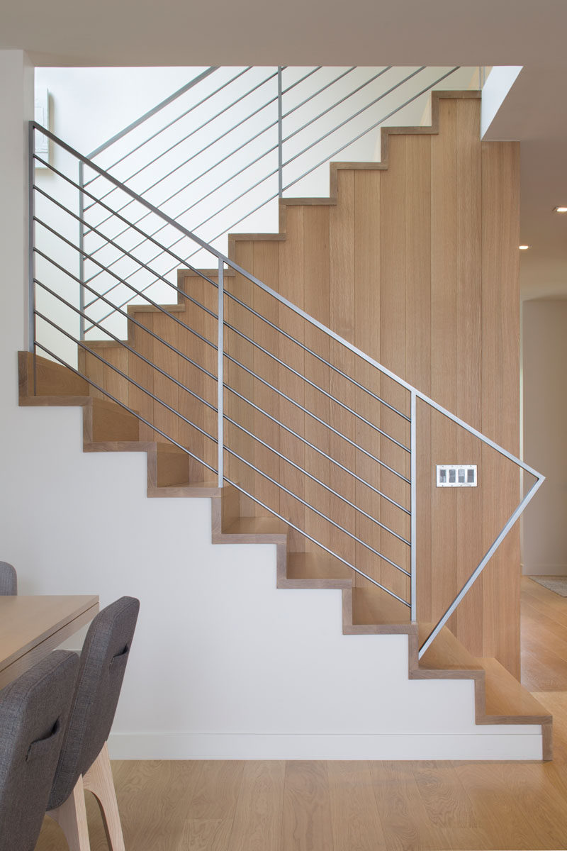 This modern house has wood stairs with a simple metal handrail that lead upstairs. #WoodStairs #Handrail #InteriorDesign