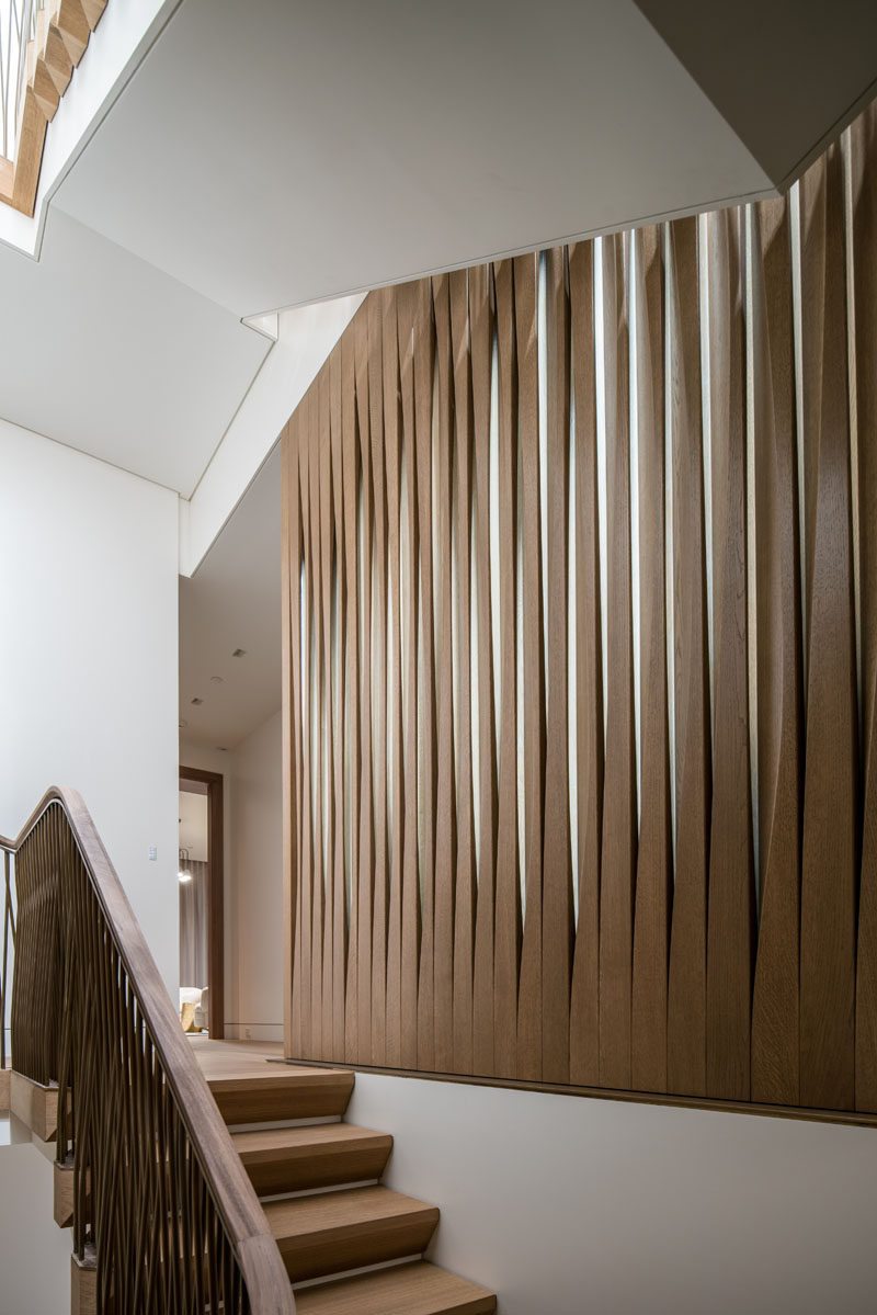 A screen of carved fumed oak and glass separates the main stairs and master dressing room in this contemporary house. #WoodScreen #Screen #ModernScreen