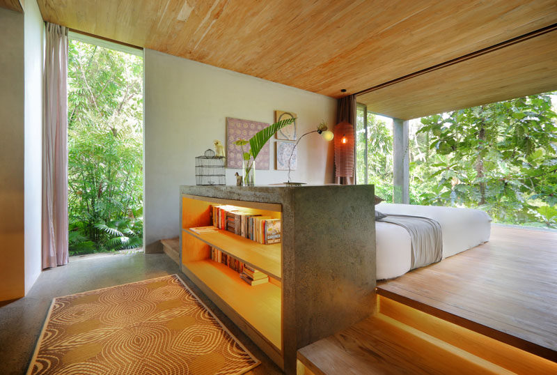 This modern bedroom that has views of the trees, has the bed raised on a wood platform. #ModernBedroom #RaisedBed