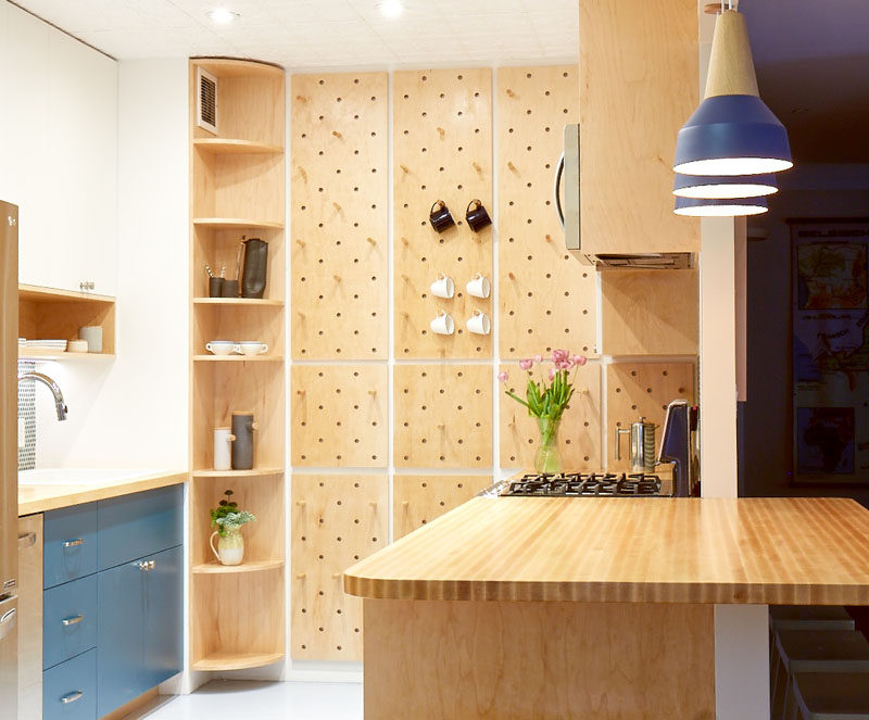 This small and modern kitchen has a custom pegboard wall, a tall curved corner shelf, and open shelves, to increase the storage the kitchen. #KitchenDesign #SmallKitchen #ModernKitchen #Pegboard #CornerShelf