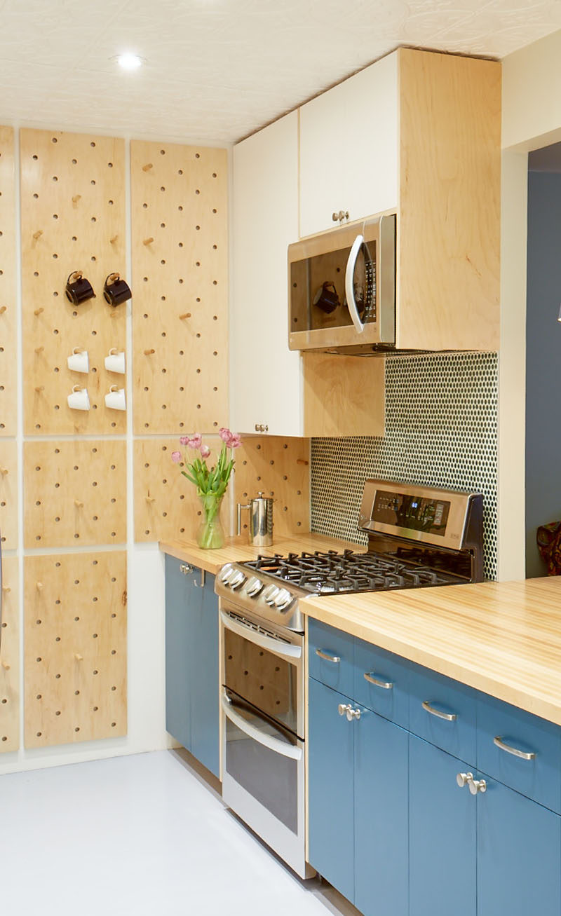 This small and modern kitchen has a custom pegboard wall, a tall curved corner shelf, and open shelves, to increase the storage the kitchen. #KitchenDesign #SmallKitchen #ModernKitchen #Pegboard