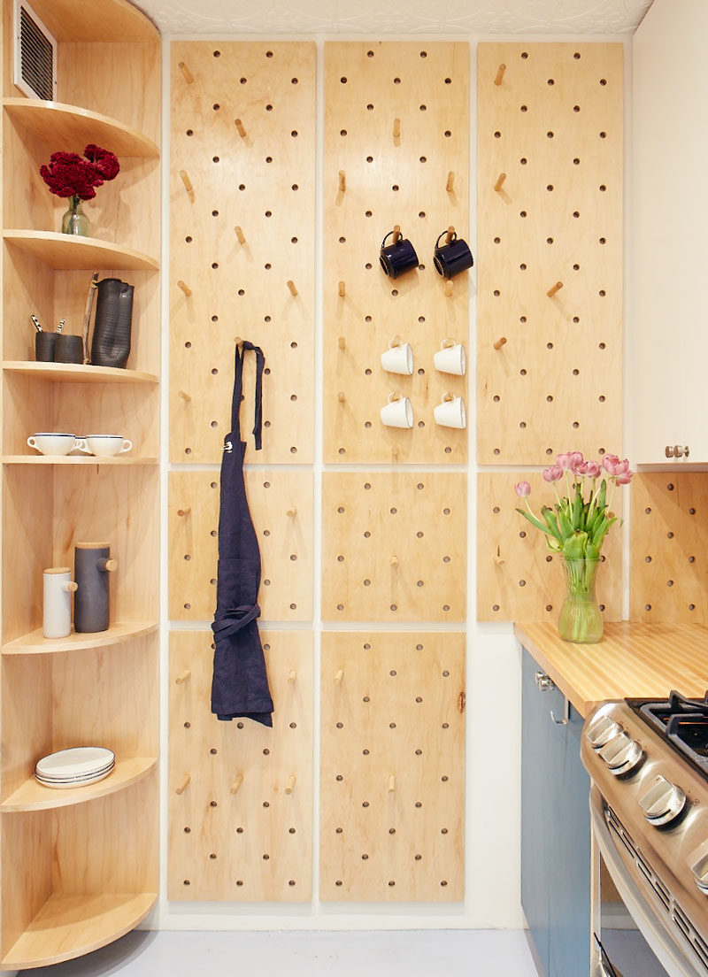 This small and modern kitchen has a custom pegboard wall, a tall curved corner shelf, and open shelves, to increase the storage the kitchen. #KitchenDesign #SmallKitchen #ModernKitchen #Pegboard #CornerShelf