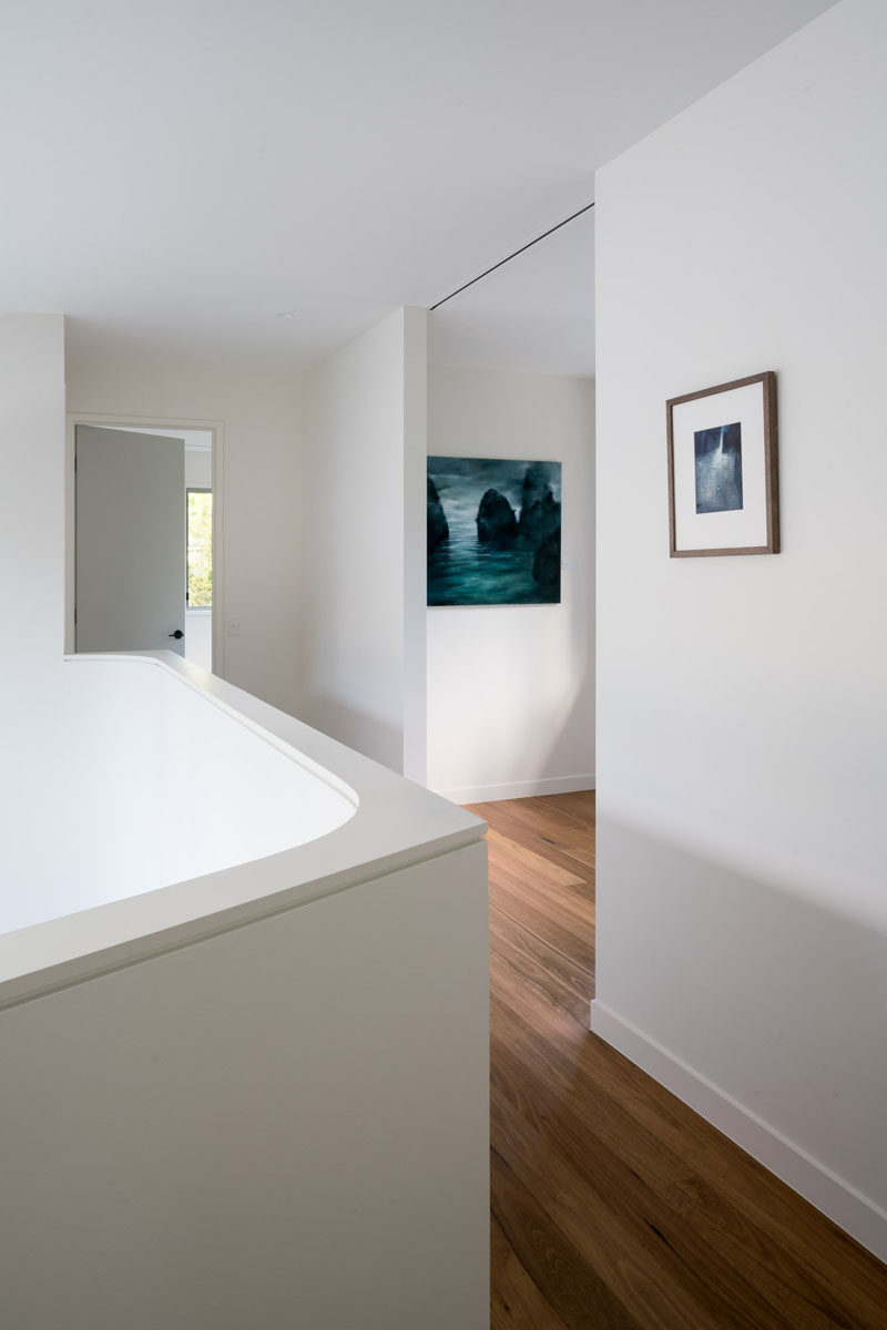 This open hallway features wood flooring and a bright white walls, creating a gallery like experience. #WhiteWalls #WoodFlooring