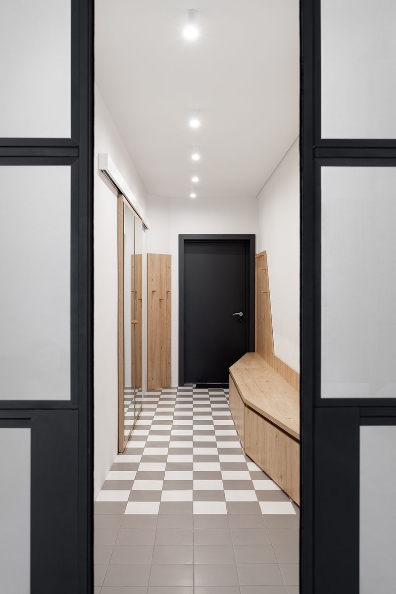 In this modern entryway, checkered tiles cover the floor, and a mirrored closet and wood bench create a place for hang coats and putting on shoes. #Entryway #InteriorDesign