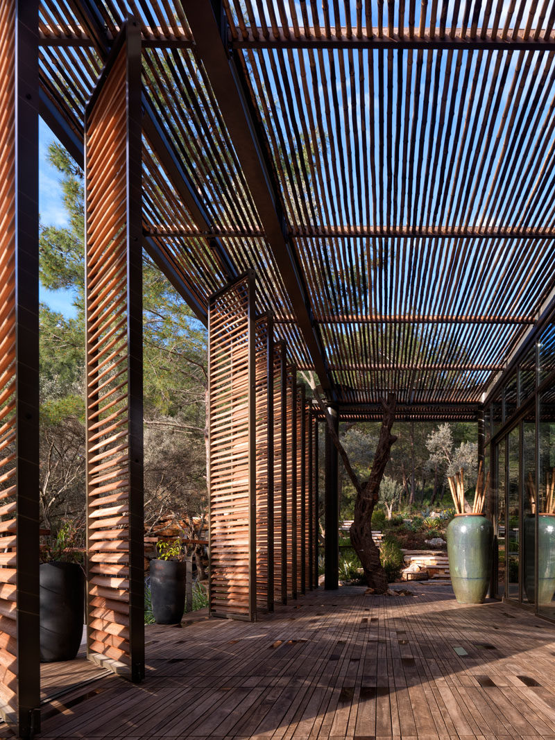 A large shaded pergola wraps around this modern club house, creating a space for visitors to relax outdoors without being in the direct sunlight. #ClubHouse #Pergola #WoodScreens