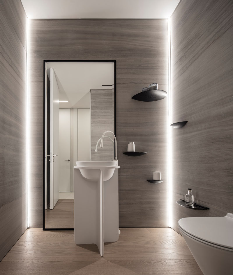 In this small bathroom, hidden lighting has been used to highlight the walls, while simple curved shelves have been mounted to the wall. #Bathroom #Lighting #Shelving #Mirror