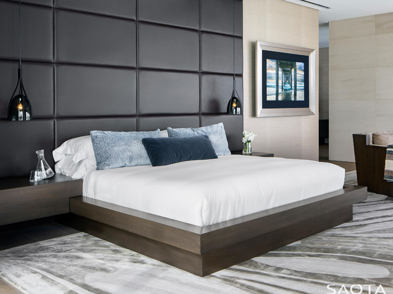This modern bedroom has a black upholstered wall as a headboard, a custom-designed wood bed frame, and single pendant lamps that hang on both sides of the bed. #Bedroom #ModernBedroom