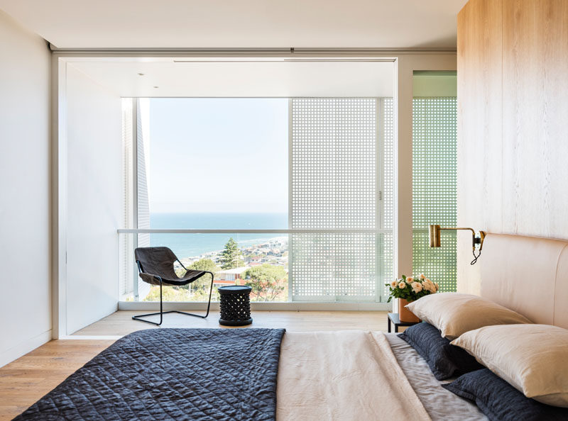 Water views can be seen from this modern master bedroom, which features a wood accent wall. #ModernBedroom #MasterBedroom