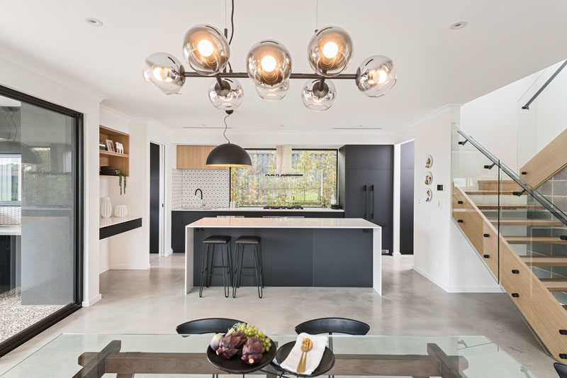 In this modern kitchen, white countertops have been paired with black cabinetry and accessories for a sleek and modern appearance. #ModernKitchen #KitchenDesign #BlackAndWhiteKitchen