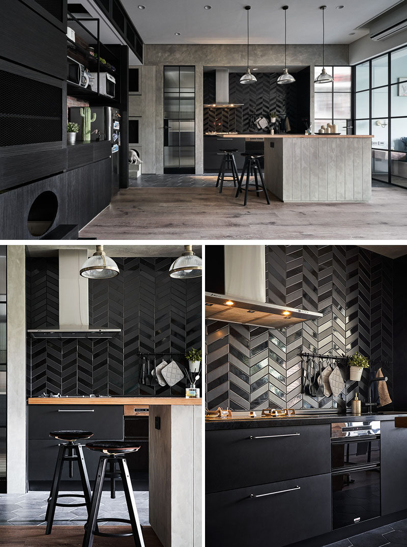 In this modern kitchen, matte and gloss black tiles have been laid in a chevron pattern, while the lower cabinets are also black. #ModernKitchen #BlackTiles #KitchenDesign