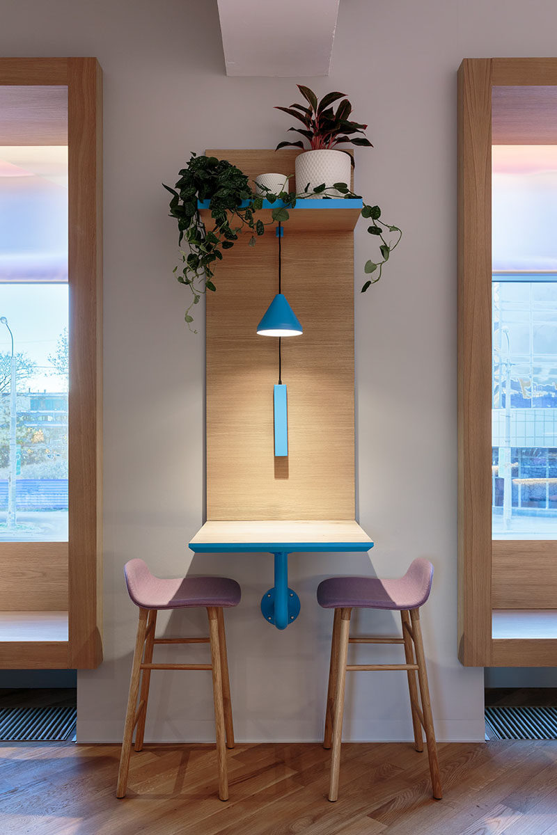 This modern cafe has sections of wood that flow from the walls and transform into tables. They also have a platform to hold plants and to hang the lighting from. #Cafe #CafeDesign #InteriorDesign