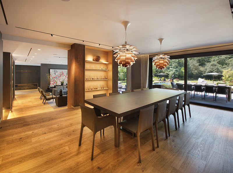 This modern dining room has a large dining table, built-in display shelves, and a large sliding glass door that opens up to an outdoor dining patio. #DiningRoom #ModernDiningRoom