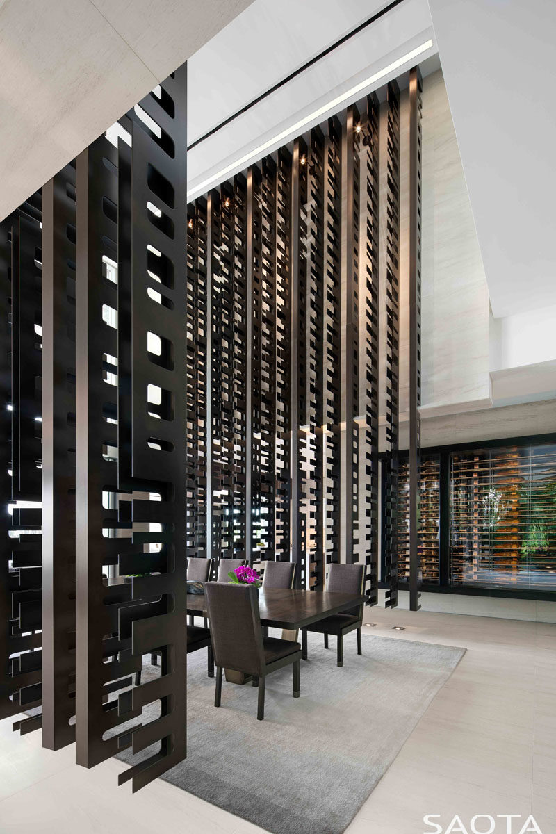 This modern house has a series of bronze screens which hang from the ceiling, creating a double height formal dining room. #ModernDiningRoom #RoomPartition #RoomDivider #Screen