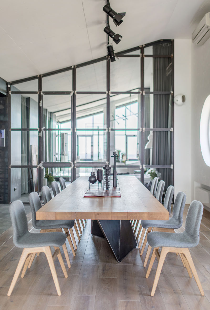 This large wood top dining table has a steel base that complements the other industrial elements in the penthouse apartment. #DiningRoom #DiningTable