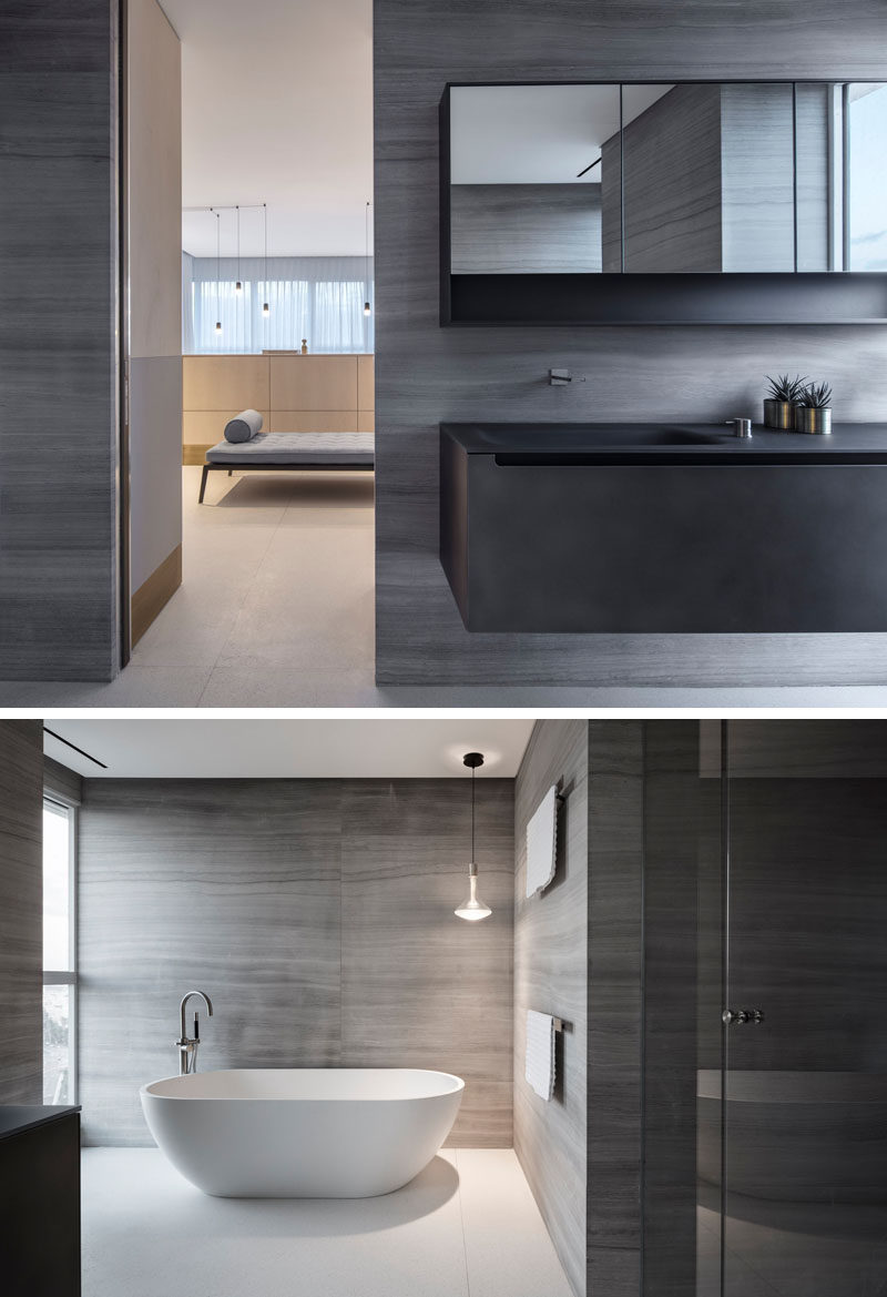 This modern ensuite bathroom has grey walls, a dark metal vanity, and a freestanding white bathtub. #ModernBathroom #EnsuiteBathroom #BathroomDesign