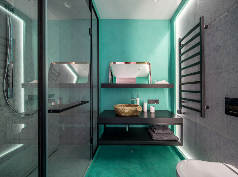 In this modern bathroom, bright turquoise on the floor and wall adds a pop of color, while the walk-in shower and opposite wall both have the same decorative tile. #ModernBathrooom #BathroomDesign