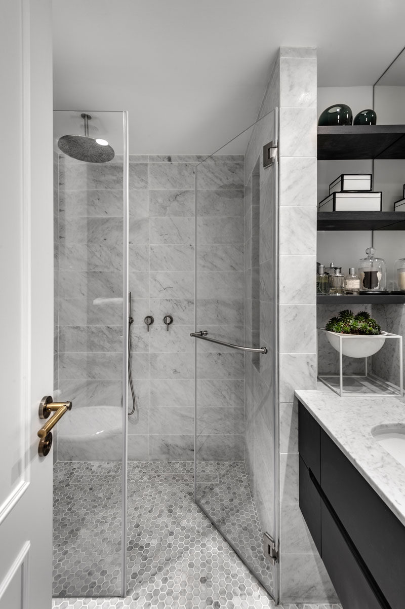 This modern bathroom design with a glass enclosed shower, has a simple grey, black and white color palette. #BathroomDesign #ModernBathroom