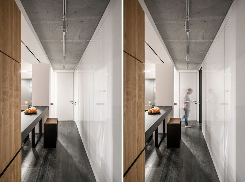 A hidden door within a wall of glossy white cabinets provides access to the other areas of this modern apartment. #WhiteCabinets #HiddenDoor