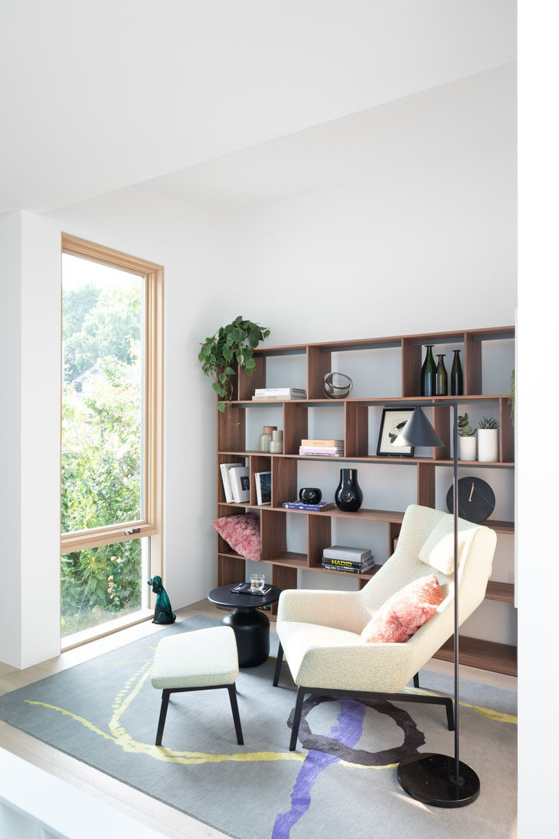 This modern house has a small den / home library space with a comfortable chair, wood shelving, and view outside. #HomeLibrary #Den #InteriorDesign