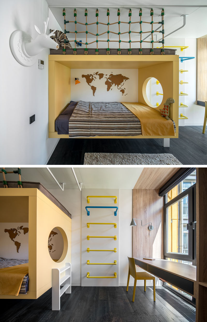 In this modern kids bedroom, the bed is surrounded by a yellow frame with a circular cutout that looks towards the window. A ladder on the wall leads up to a a reading nook above the bed, while against the window, a custom designed desk sits within a wood frame. #ModernKidsBedroom #KidsBedroom #ChildsBedroom