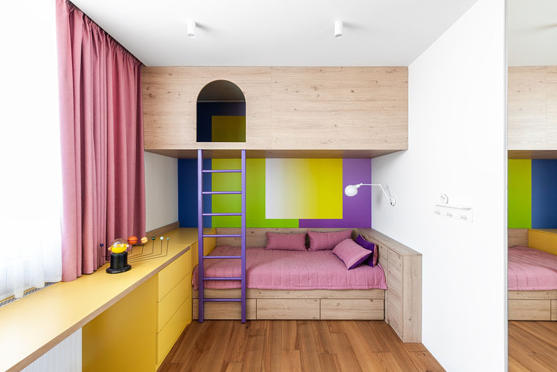 In this bright and fun bedroom, there's a reading nook / play area that can only be reached via a ladder, while below is a bed with storage and and a yellow desk area. #BedroomDesign #InteriorDesign