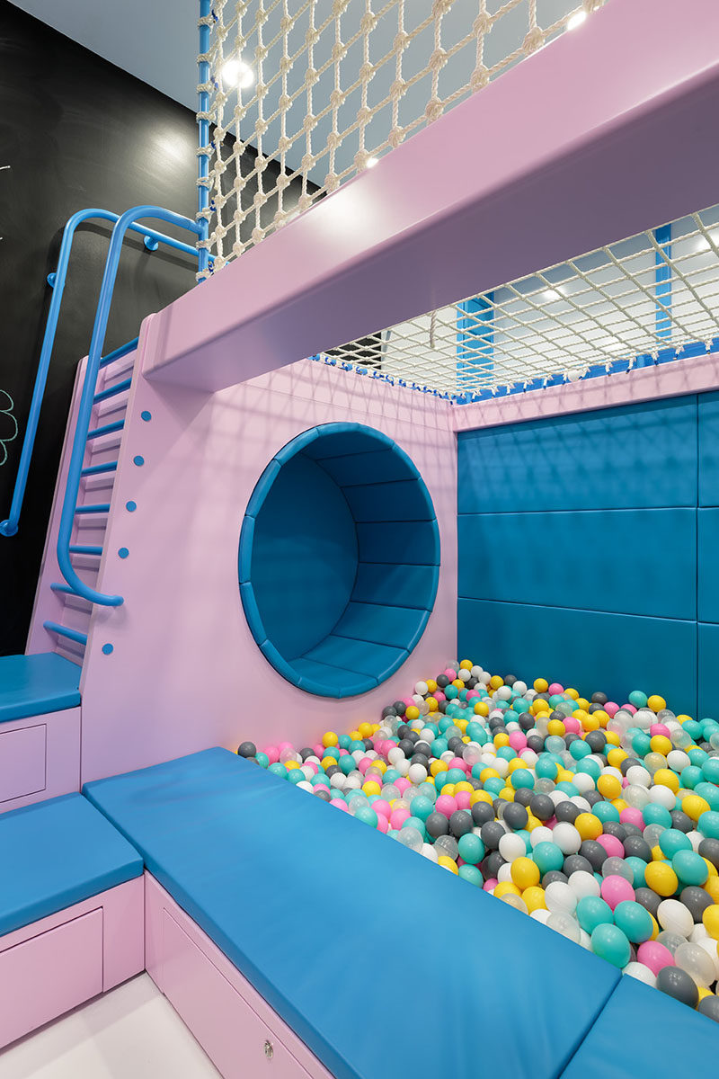 This modern kids play area with a ball pit, seating nook, a chalkboard wall, and a ladder that leads to a net for relaxing in. #KidsPlayArea #BallPit