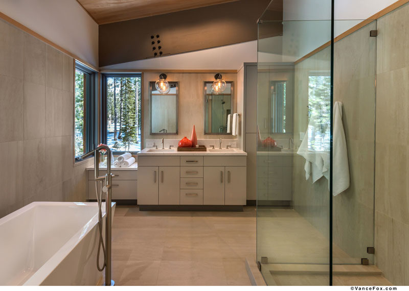 This modern master bathroom has a stand-alone soaking tub, a glass shower surround and a vanity that runs the length of the wall. #MasterBathroom #ModernBathroom