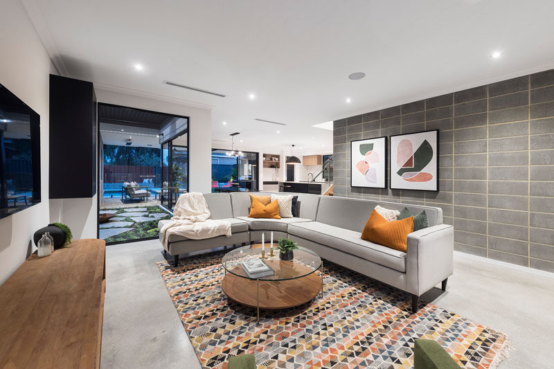 This modern living room has a curved grey couch that's anchored in the room by a colorful geometric rug. #LivingRoom #ModernLivingRoom