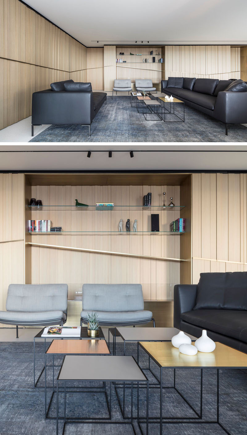 The main social areas of this modern apartment are all open plan, with the living room featuring at one end. Built into the wall is an alcove with glass shelves. #LivingRoom #ModernInterior #Shelving #WoodWalls