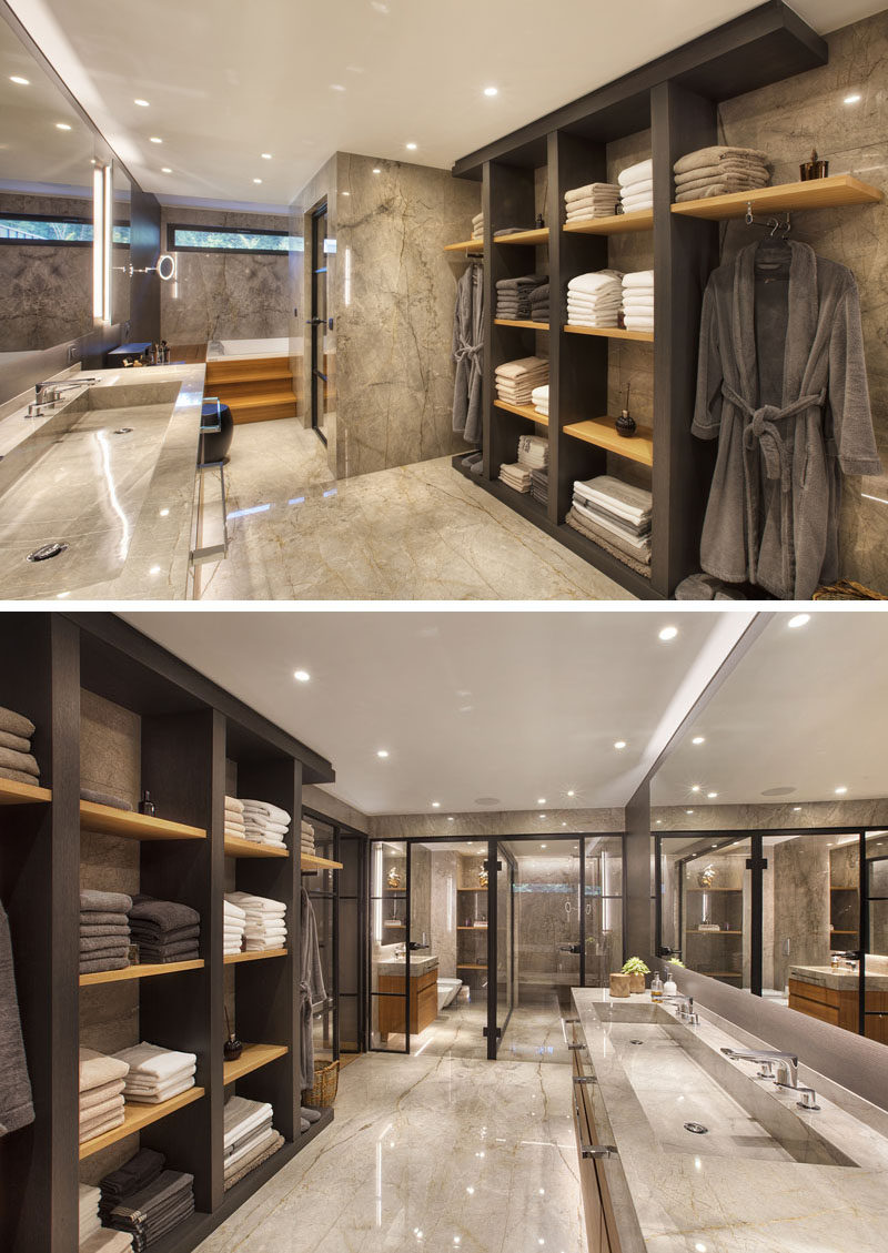 In this modern master bathroom, there's open shelving with places to hang clothes, a long double trough sink, a built-in bath, and a shower with a black-framed glass shower screen. #ModernBathroom #MasterBathroom #BathroomDesign