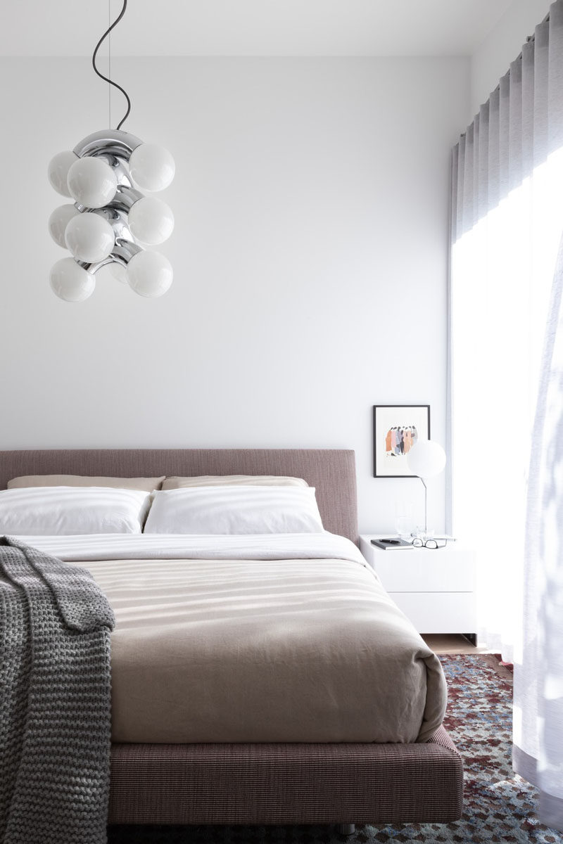 In this modern master bedroom, a neutral color palette creates a calm space, while a AndLight Vine 5 Pendant hangs from the ceiling. #MasterBedroom #ModernBedroom #BedroomDesign