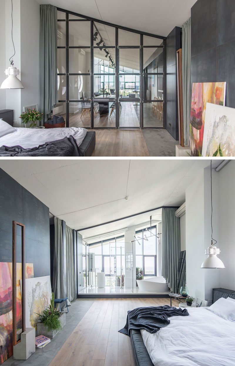 Partitioned off from the social areas of the apartment by a wall of steel-framed glass, is the master bedroom. Steel paneling covers the wall opposite the bed, while the sloped ceiling is accentuated by the glass frames. #MasterBedroom #GlassPanels #EnsuiteBathroom