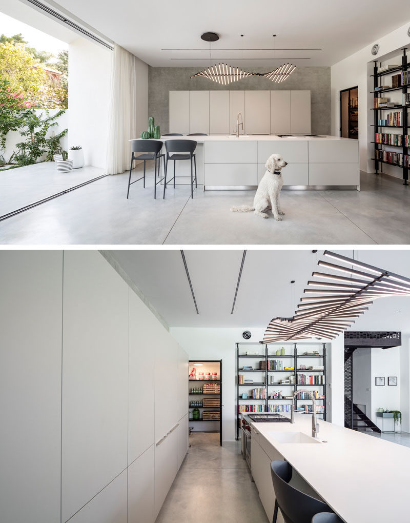 This kitchen has minimalist cabinetry for a sleek and modern look, while a sculptural light fixture hangs above the island. #KitchenDesign #ModernKitchen #MinimalistKitchen