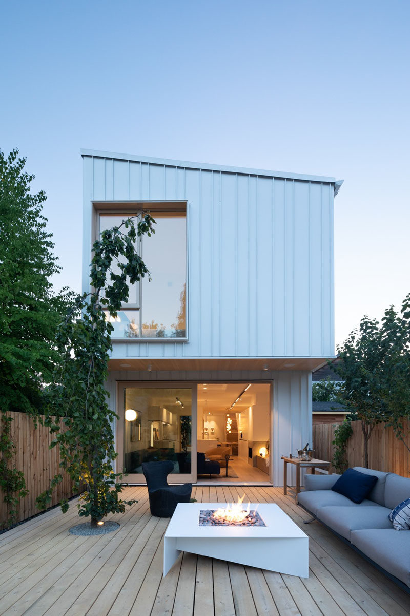 The back patio of this modern house, which is made from wood, is home to a couple of trees and an outdoor living room with a fire table. #Patio #OutdoorSpace