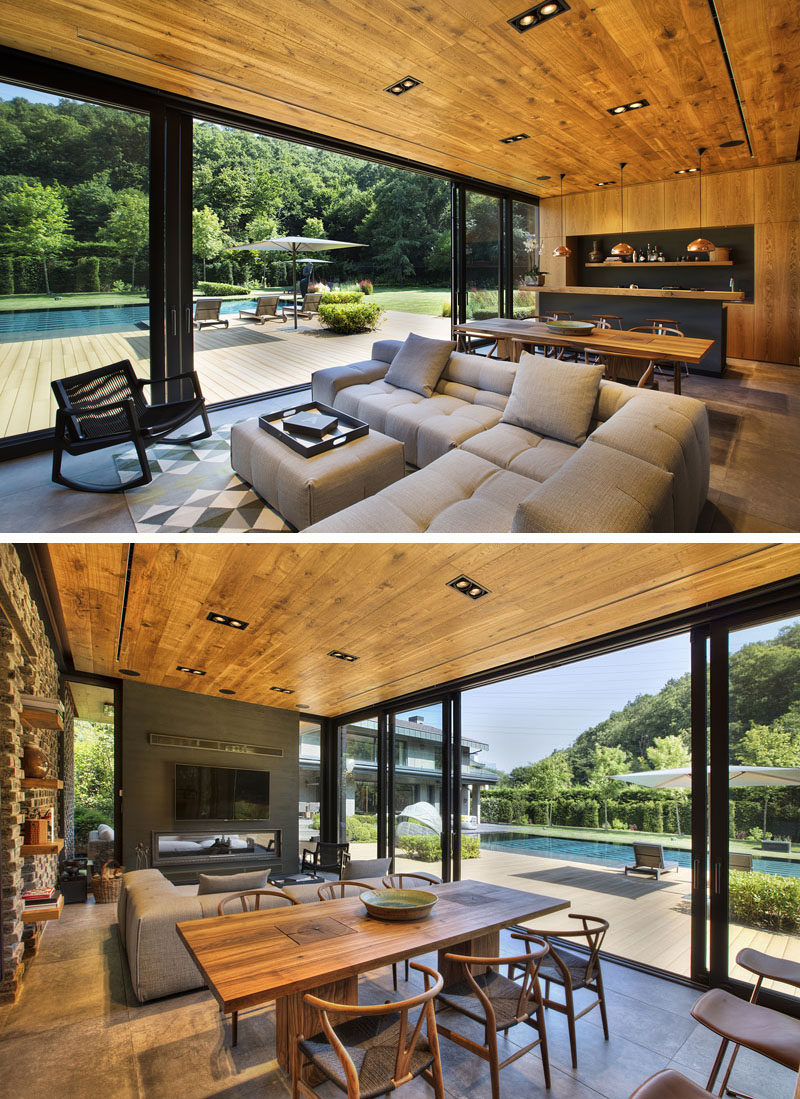 Inside this modern poolhouse, there's an open floor plan with a lounge area, a dining space, and a kitchen. Sliding glass doors open the space directly to the pool deck. #ModernPoolhouse #Poolhouse #InteriorDesign