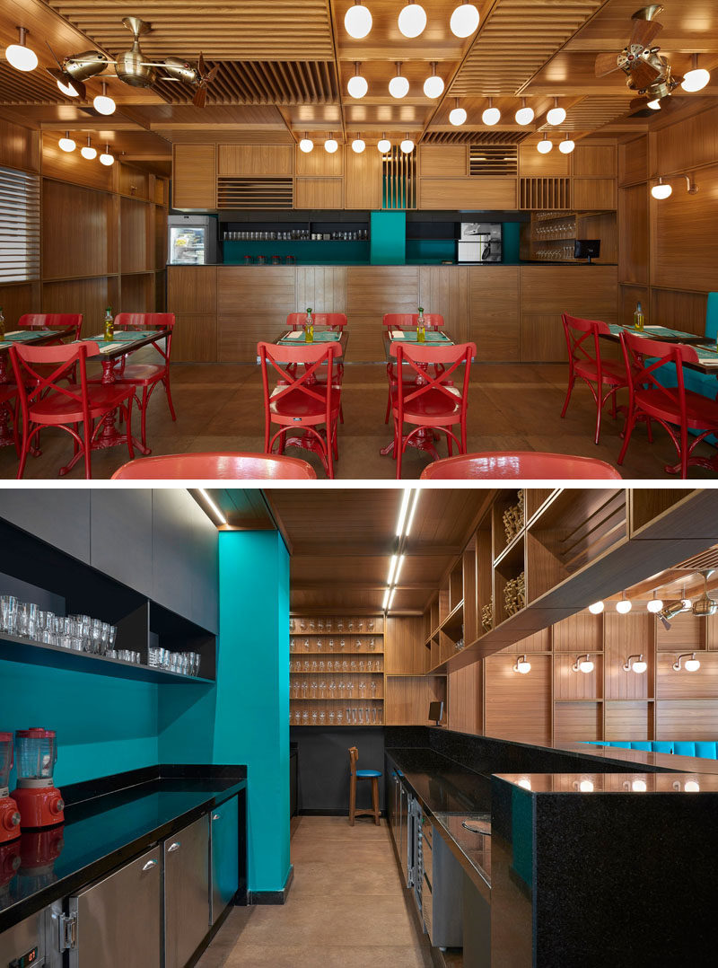 The service area of this modern restaurant has a blue accent wall to match the banquette seating, and black counters complement the black upper cabinets. #RestaurantDesign #ModernRestaurant