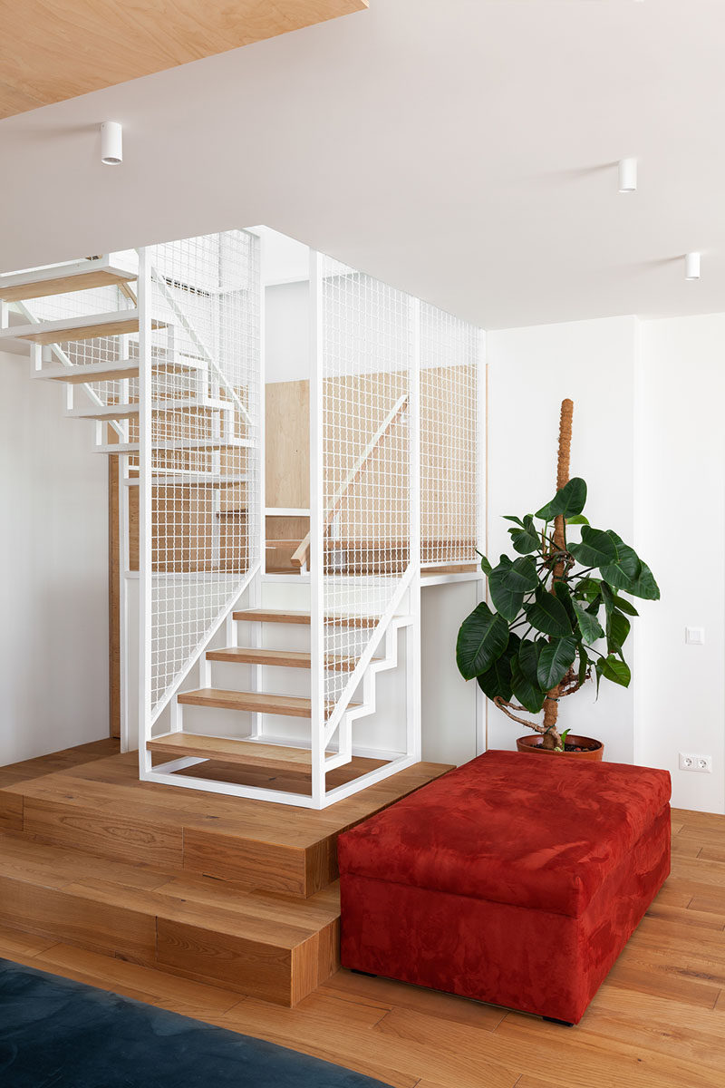 In this modern apartment, white and wood stairs located in the corner of the living room lead to the private areas upstairs. #Stairs #StairDesign