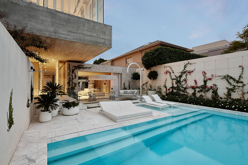 This modern house has a swimming pool that's surrounded by marble tiling. The use of outdoor greenery and an all white colour palate gives the outdoor space the impression of an exotic oasis located within an inner-city environment. #ModernSwimingPool #OutdoorSpace