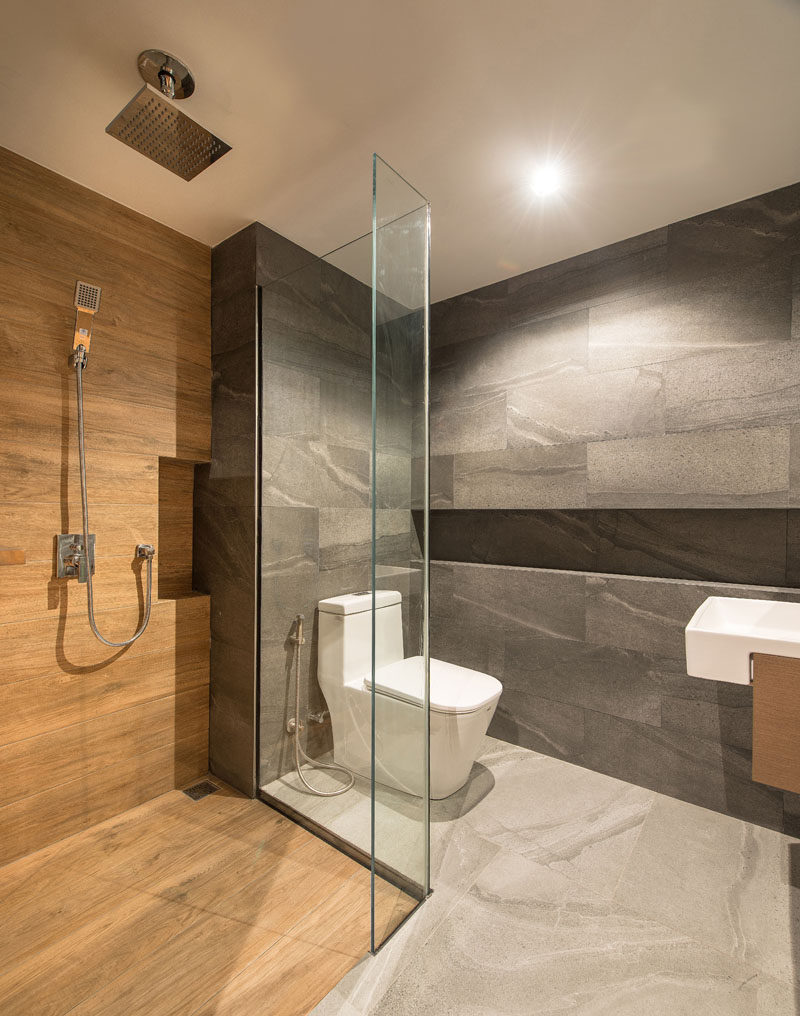 This modern bathroom uses a mixture of grey tiles, wood, and glass, to create a calm experience. #ModernBathroom #BathroomDesign