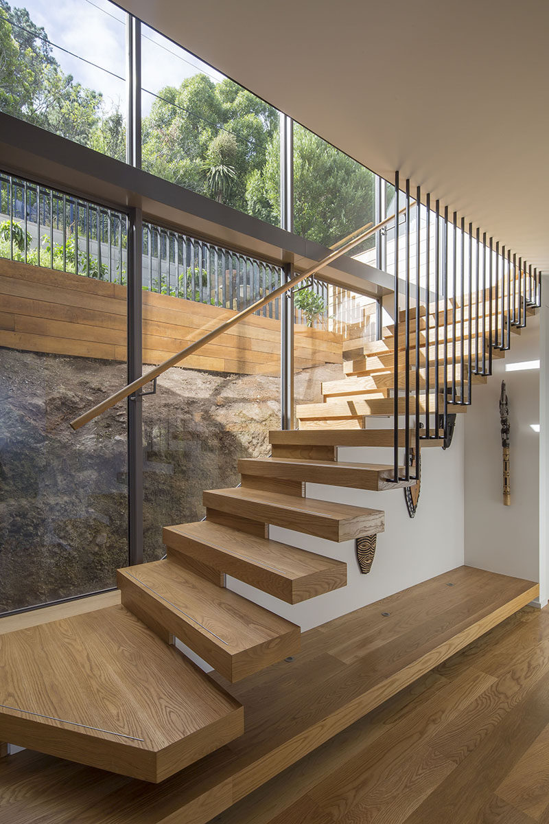 Connecting the various levels of this modern house are cantilevered wood stairs that have a view of the natural rock face. #WoodStairs #Cantilever #StairDesign