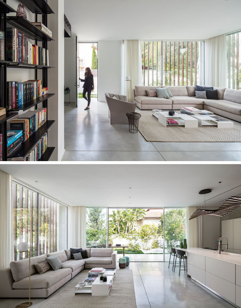 Inside this modern house, the tall front door opens into the living room, which also shares the room with the kitchen. A large sliding glass door opens the interior to the backyard, creating an indoor/outdoor living environment. #ModernInterior #LivingRoom #OpenPlan