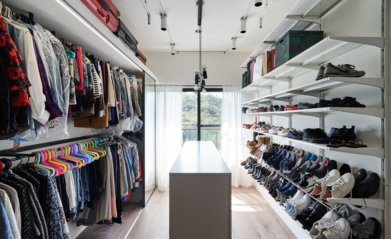 This modern walk-in closet makes use of the natural light from the floor-to-ceiling windows, and the white cabinetry and shelves provide ample space for clothes and shoes. #WalkInCloset #Closet #Storage