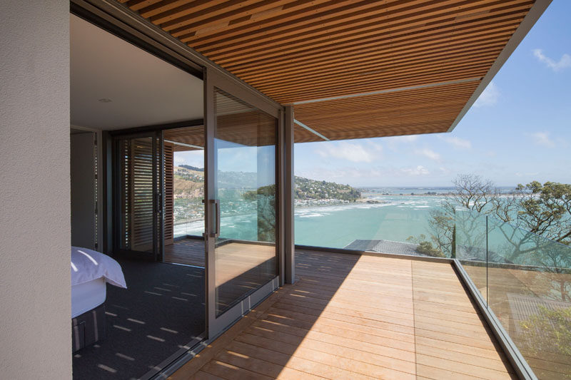 This modern bedroom has sliding doors that open to a balcony with seamless ocean views. #Bedroom #Balcony #GlassRailing